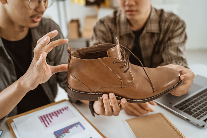 Two staff members discussing a sample shoe.